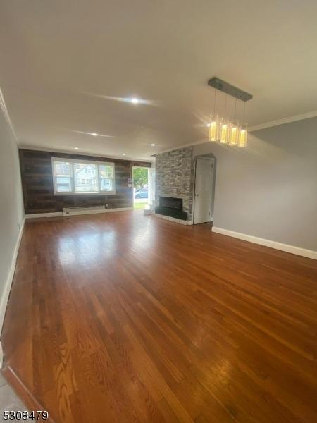 unfurnished living room featuring crown molding, a fireplace, baseboards, and wood finished floors