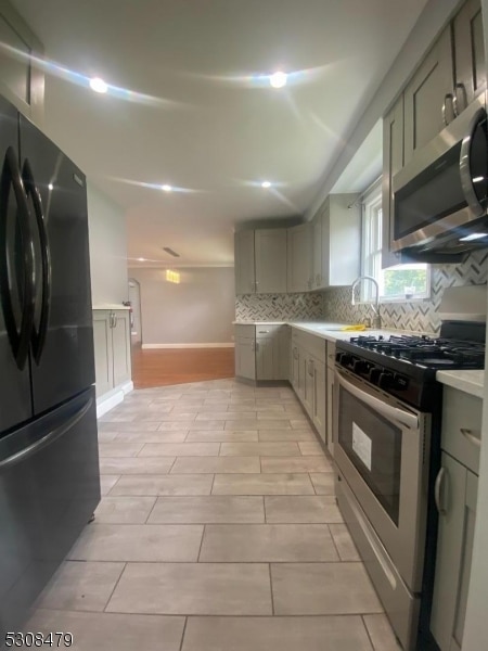 kitchen with sink, stainless steel appliances, light tile patterned flooring, and tasteful backsplash