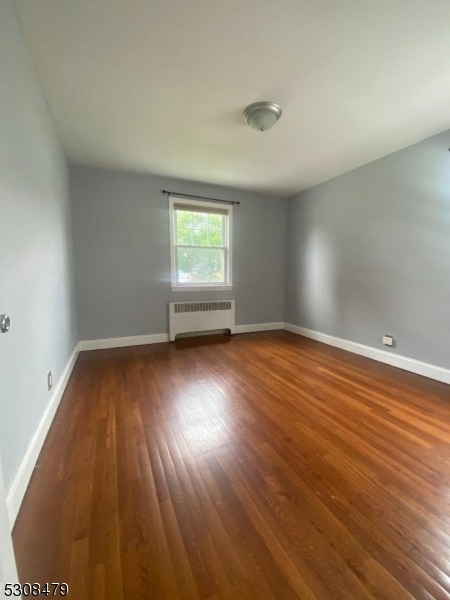 empty room with radiator and dark wood-type flooring