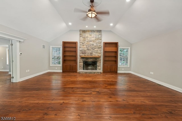 unfurnished living room featuring vaulted ceiling, dark hardwood / wood-style flooring, a stone fireplace, and ceiling fan