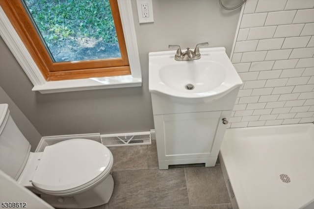 bathroom with vanity, a tile shower, tile patterned floors, and toilet