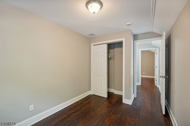 unfurnished bedroom featuring lofted ceiling, dark wood-type flooring, and a closet