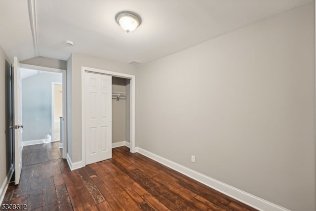 unfurnished bedroom with lofted ceiling, dark hardwood / wood-style floors, and a closet