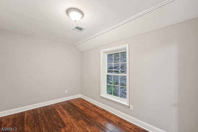 spare room featuring lofted ceiling and dark hardwood / wood-style flooring