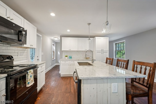 kitchen with a kitchen bar, sink, a center island with sink, and black appliances