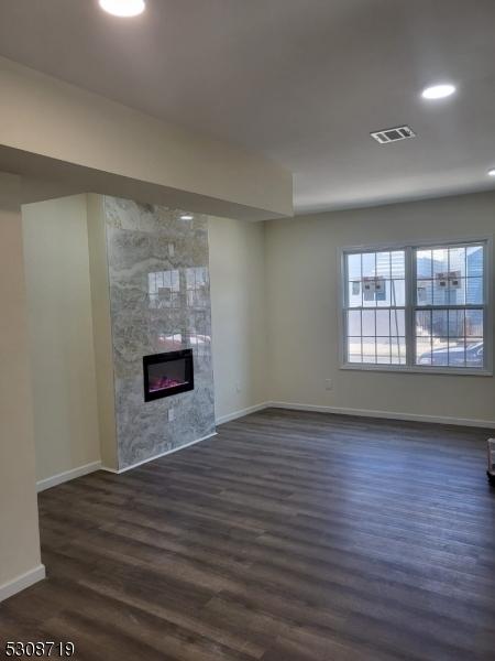 unfurnished living room with a tiled fireplace and dark hardwood / wood-style floors