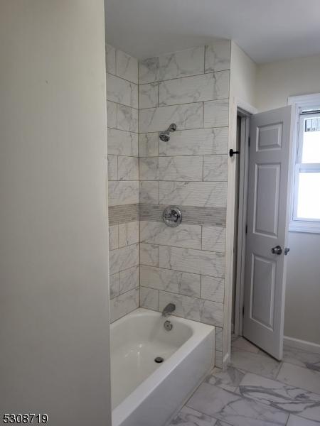 full bathroom with marble finish floor, baseboards, and bathing tub / shower combination