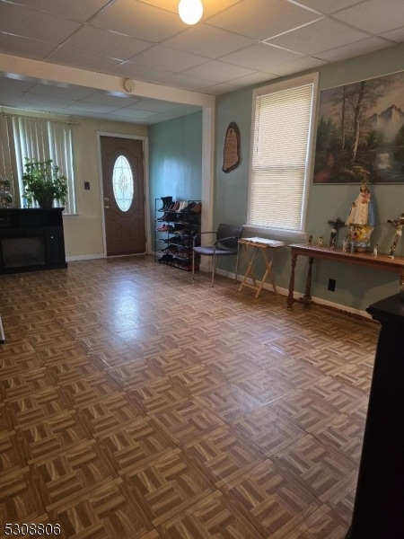 entrance foyer featuring a drop ceiling and dark parquet flooring