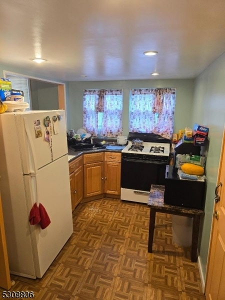 kitchen with sink, white appliances, and dark parquet flooring