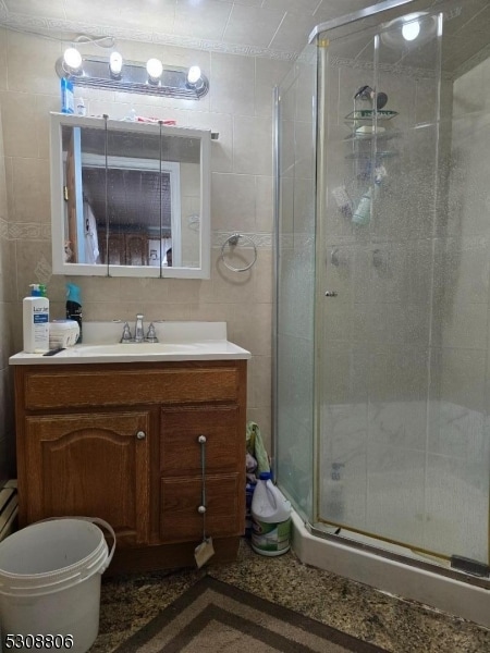 bathroom with a shower with door, toilet, vanity, and tile walls