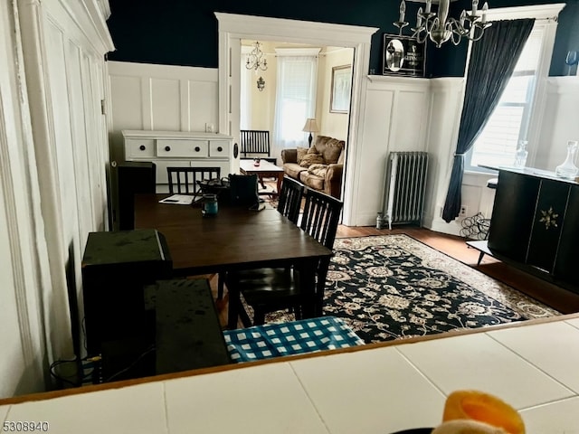 dining area featuring radiator heating unit, a chandelier, and wood-type flooring