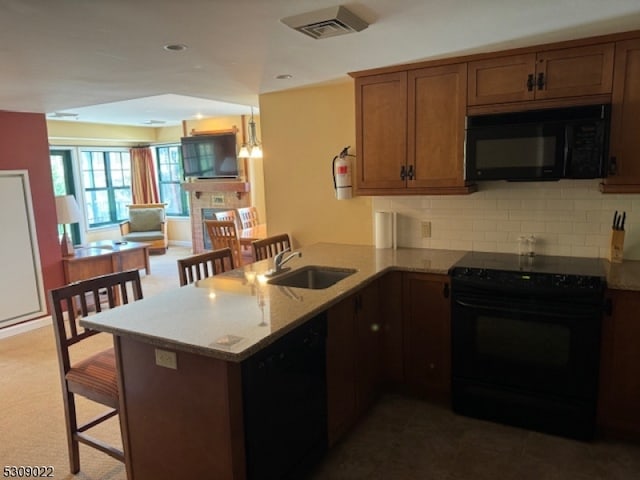 kitchen featuring sink, black appliances, kitchen peninsula, a kitchen breakfast bar, and dark colored carpet