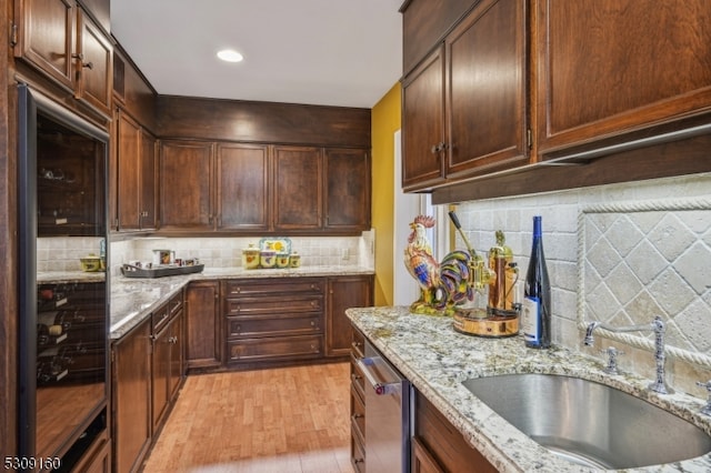 kitchen with light stone counters, light hardwood / wood-style flooring, sink, and tasteful backsplash