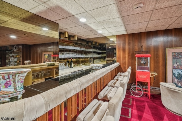 bar featuring wooden walls, carpet floors, and a paneled ceiling