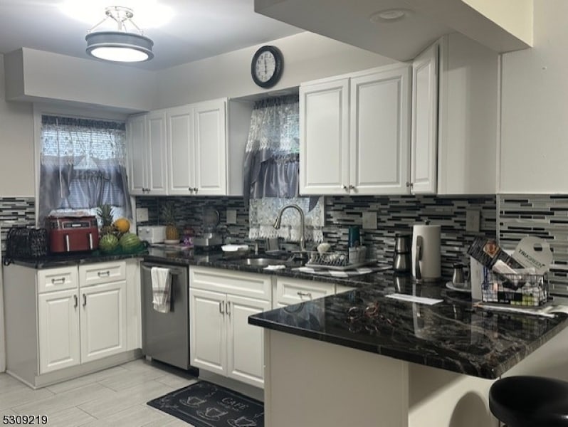 kitchen featuring white cabinets, dishwasher, sink, kitchen peninsula, and tasteful backsplash