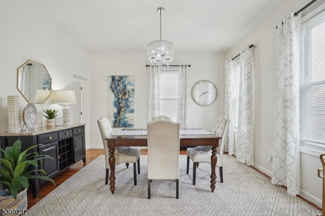 dining space featuring baseboards, light wood finished floors, and an inviting chandelier