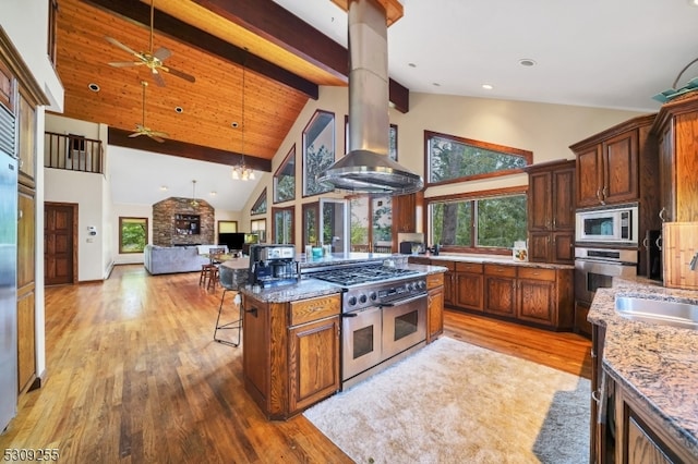 kitchen with dark stone counters, high vaulted ceiling, light hardwood / wood-style flooring, appliances with stainless steel finishes, and beam ceiling