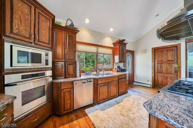 kitchen with light hardwood / wood-style flooring, sink, a baseboard radiator, built in appliances, and exhaust hood