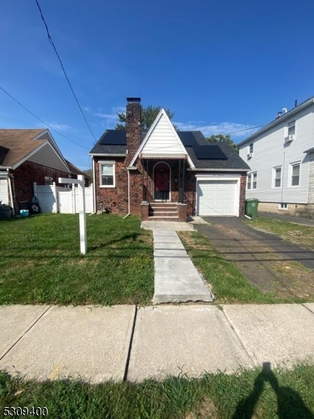 view of front facade with solar panels, a front yard, and a garage