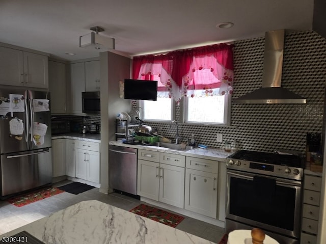 kitchen with backsplash, wall chimney range hood, appliances with stainless steel finishes, and light tile patterned flooring