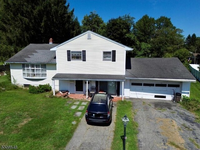 split level home featuring a porch, a garage, and a front lawn