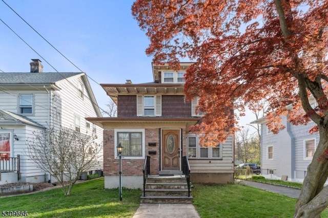 view of front of home with brick siding, a front yard, and entry steps