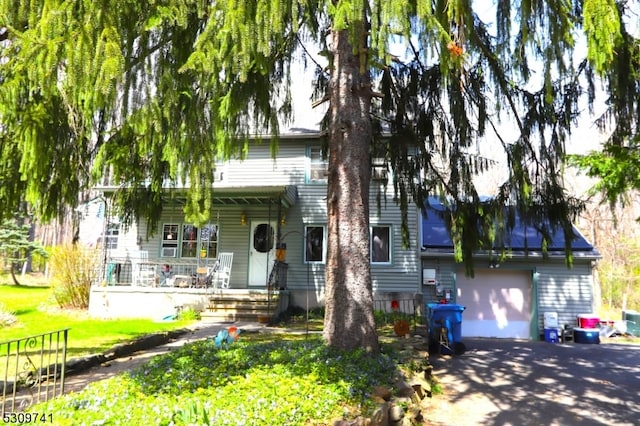 view of front of house with a garage, covered porch, and a front lawn