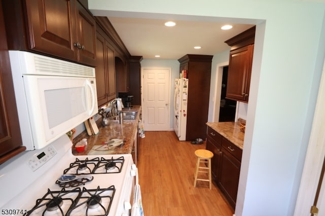 kitchen with white appliances, light stone counters, light hardwood / wood-style floors, and sink