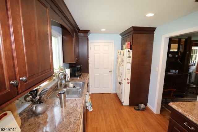 kitchen with sink, white fridge, light stone countertops, and light hardwood / wood-style floors