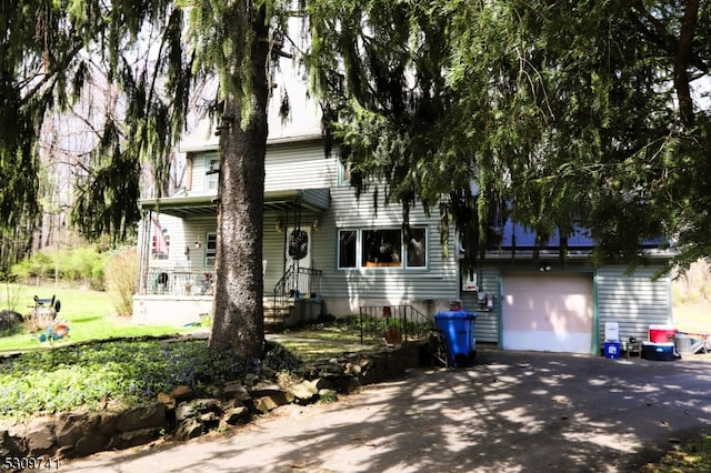 view of front of home with a garage, a front yard, and covered porch