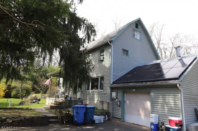 back of house featuring cooling unit, solar panels, and a garage