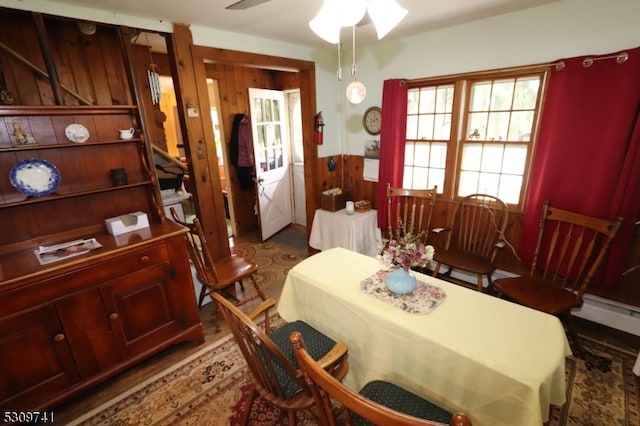 dining room with baseboard heating, ceiling fan, and wooden walls