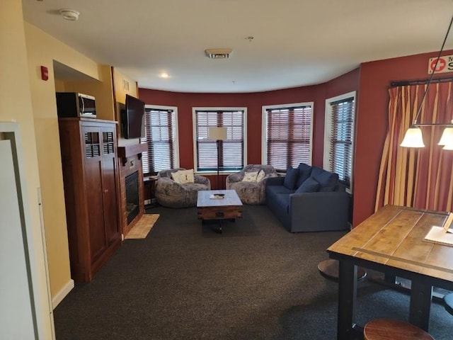 living room featuring a fireplace with flush hearth, carpet, and visible vents