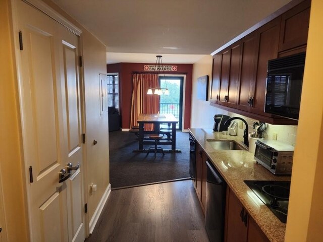 kitchen featuring dark hardwood / wood-style floors, decorative light fixtures, light stone countertops, black appliances, and sink