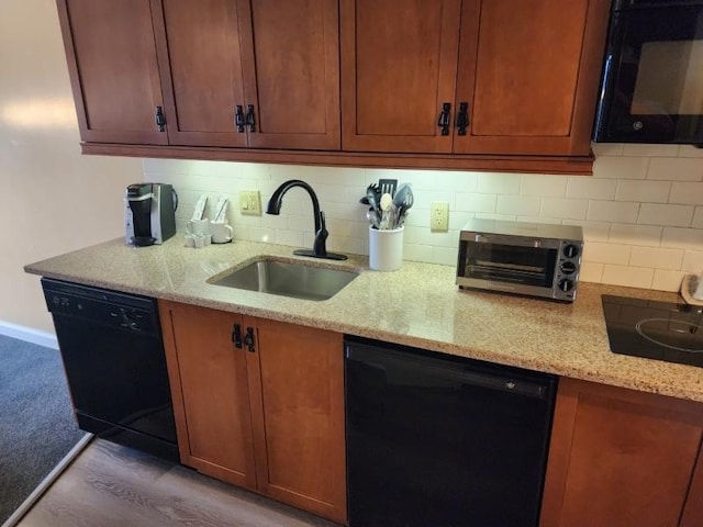 kitchen featuring black appliances, light stone counters, backsplash, and a sink