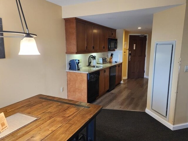 kitchen featuring decorative light fixtures, dark hardwood / wood-style flooring, black appliances, backsplash, and sink