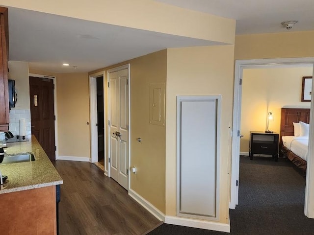 hall featuring recessed lighting, a sink, dark wood finished floors, and baseboards