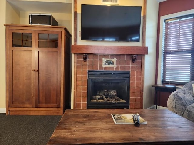 living area featuring a wealth of natural light, a tile fireplace, and visible vents