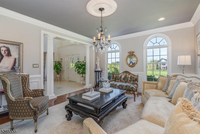 living room featuring hardwood / wood-style flooring, a chandelier, crown molding, and ornate columns