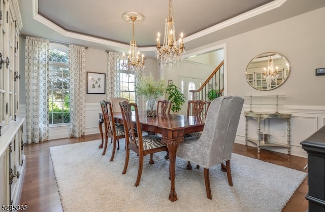 dining space with a tray ceiling, hardwood / wood-style flooring, and an inviting chandelier