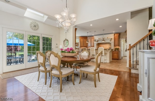 dining space with a skylight, light hardwood / wood-style flooring, and an inviting chandelier