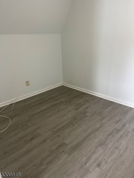 additional living space with dark wood-type flooring and vaulted ceiling