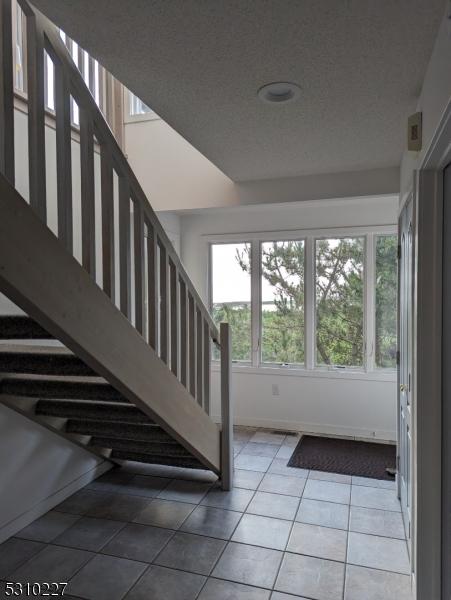 stairway featuring tile patterned floors and a textured ceiling