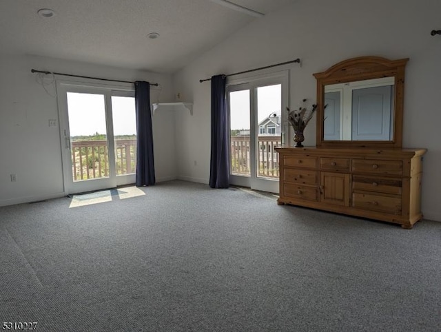 carpeted empty room featuring vaulted ceiling and plenty of natural light