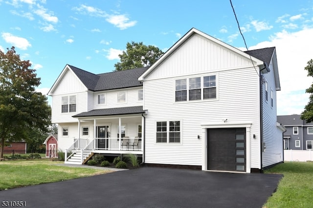 view of front of property featuring a garage, covered porch, and a front yard