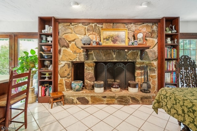 tiled living room with a stone fireplace and a textured ceiling