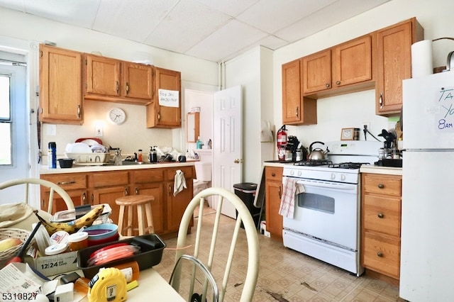 kitchen featuring a paneled ceiling and white appliances