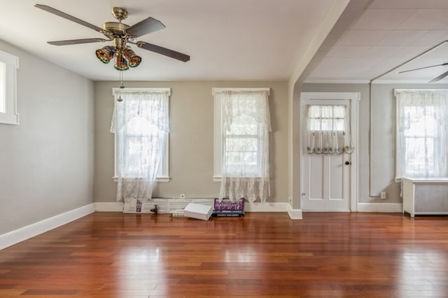 interior space with dark hardwood / wood-style floors, ceiling fan, radiator, and a wealth of natural light