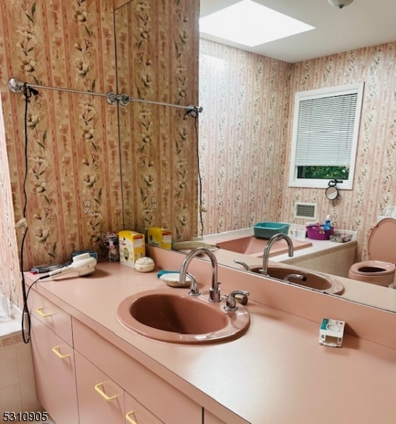 bathroom featuring vanity, a skylight, tile patterned flooring, and toilet