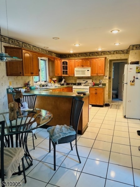 kitchen with white appliances, kitchen peninsula, and light tile patterned flooring